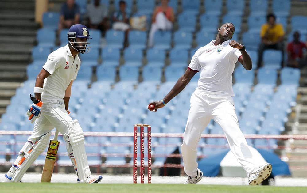 West Indies captain Jason Holder bowls under the watch of India`s batsman Lokesh Rahul on day one of their third cricket Test match