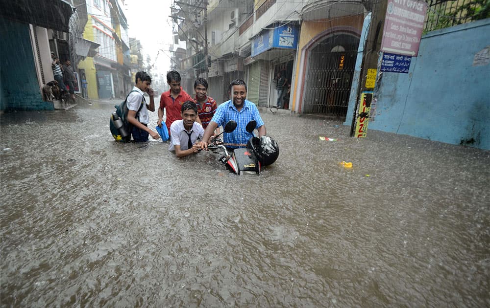 Students pushing a bike at a waterlogged road after heavy rains in Patna