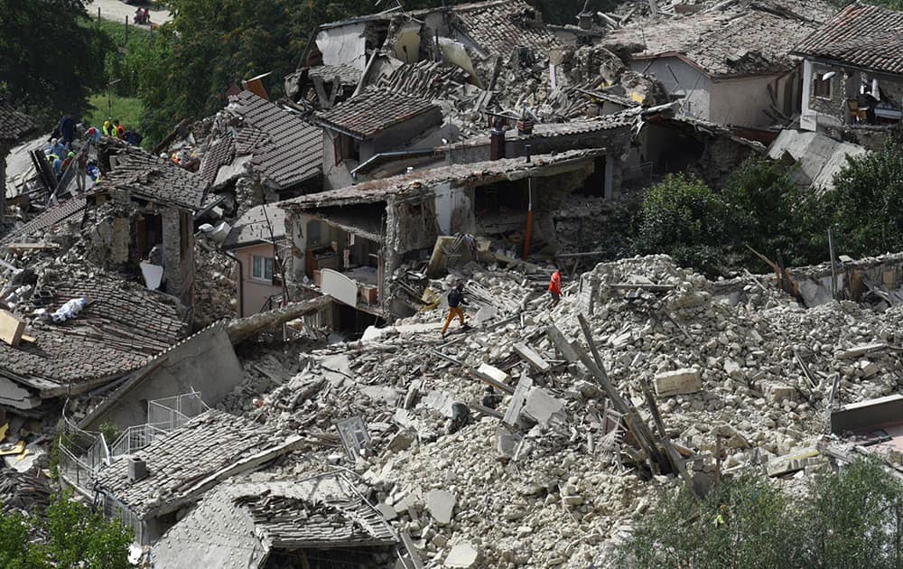 Rescuers are seen working in the rubble of collapsed and damaged houses in the village of Pescara del Tronto, central Italy