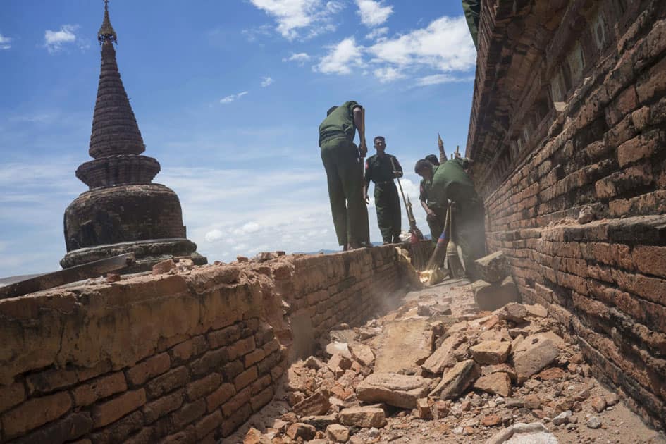 Military personnel clear debris at a temple