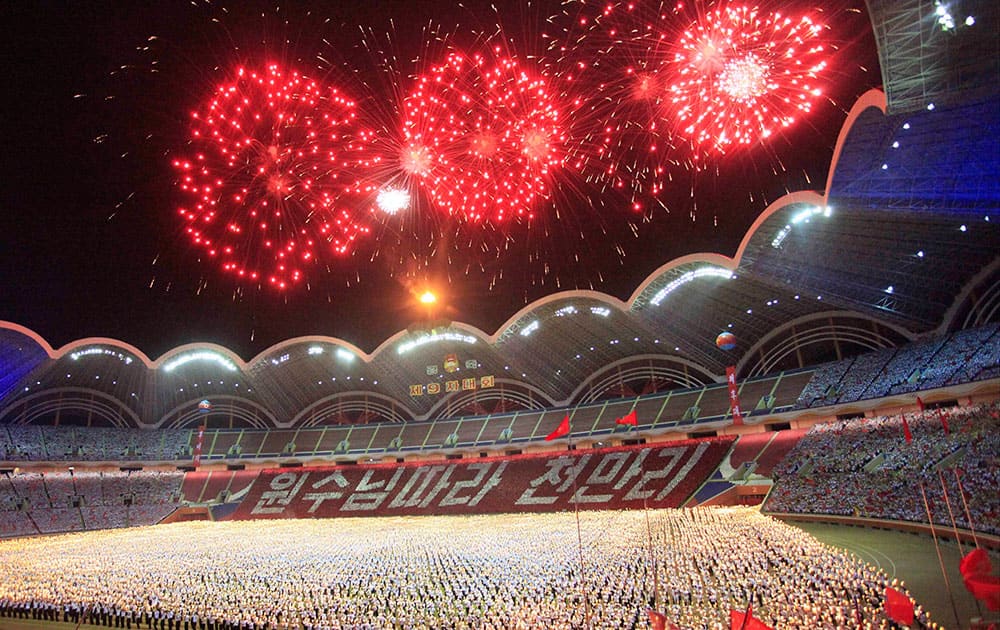 Participants carry torches on the field during a fireworks display as they parade during a celebration of the gathering of the country's main youth league at May Day Stadium