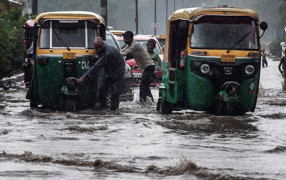 Vehicles make their way through floodwaters on a street after heavy rainfall in New Delhi