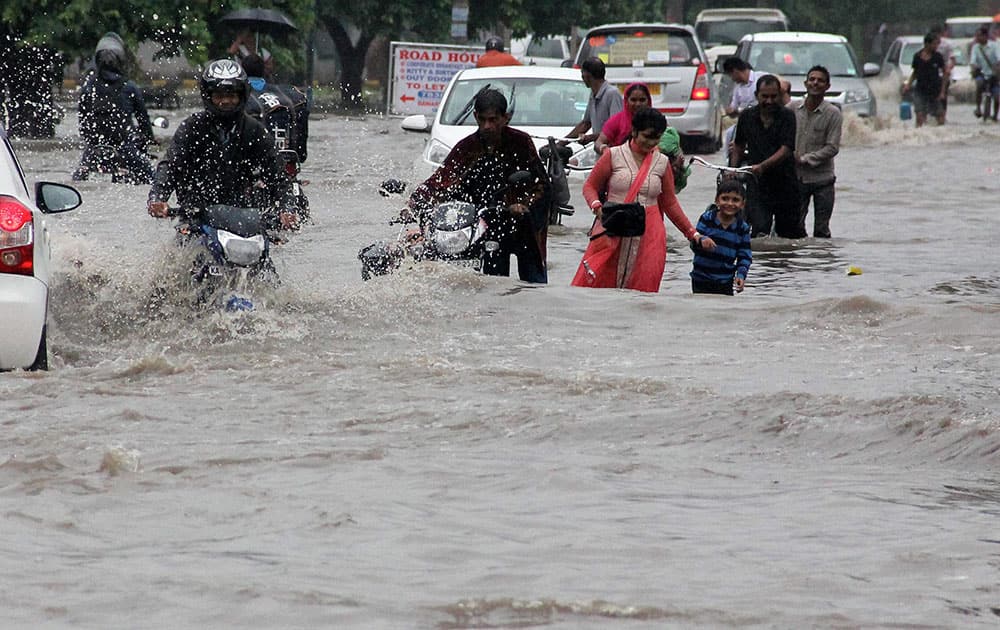 people make their way through floodwaters on a street during heavy rainfall in Gurgaon people make their way through floodwaters on a street during heavy rainfall in Gurgaon