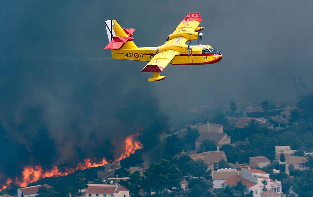 A plane flies as a wildfire burns nearby Benitachel village, near Benidorm