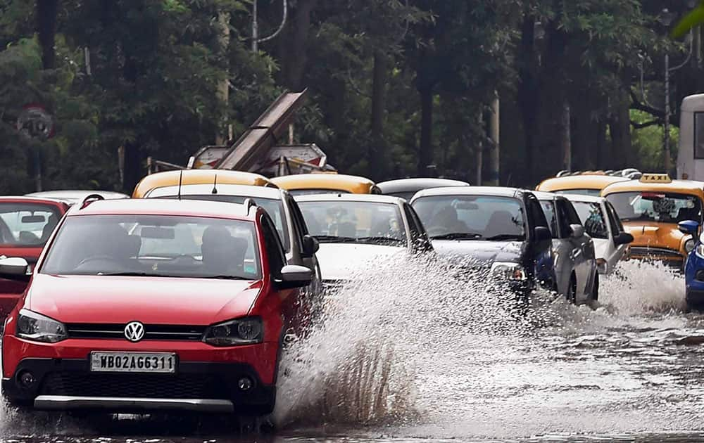 Cars make their way through a water logged road after heavy rains, in Kolkata