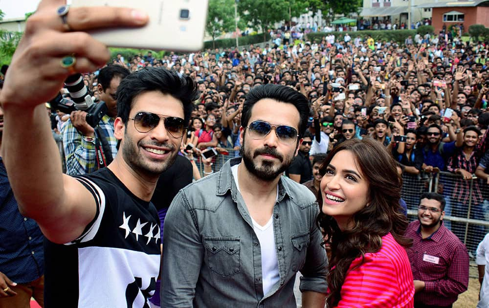 Gaurav Arora (L), Emraan Hashmi and Kriti Kharbanda take a selfie with their fans during a promotional event of their upcoming film Raaz Reboot at a college in Ahmedabad