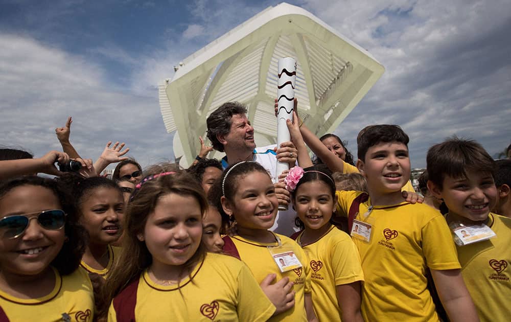 Director of the Museum of Tomorrow, Ricardo Piquet, center, holds the Paralympic torch as he poses with school students during the torch relay in front of the museum