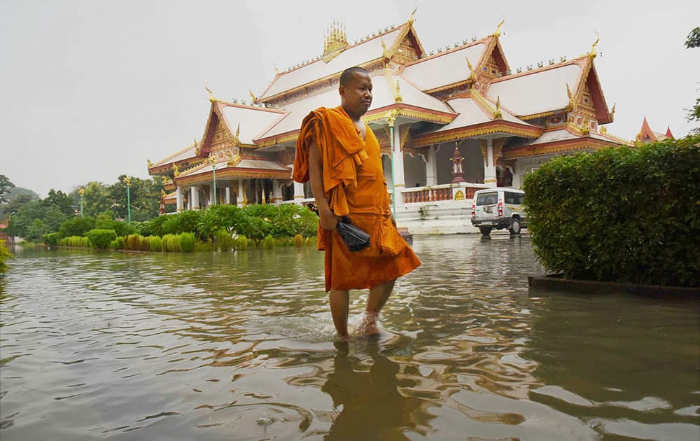 A monk wades through water in front of a flood-hit Wat Pa temple in Gaya