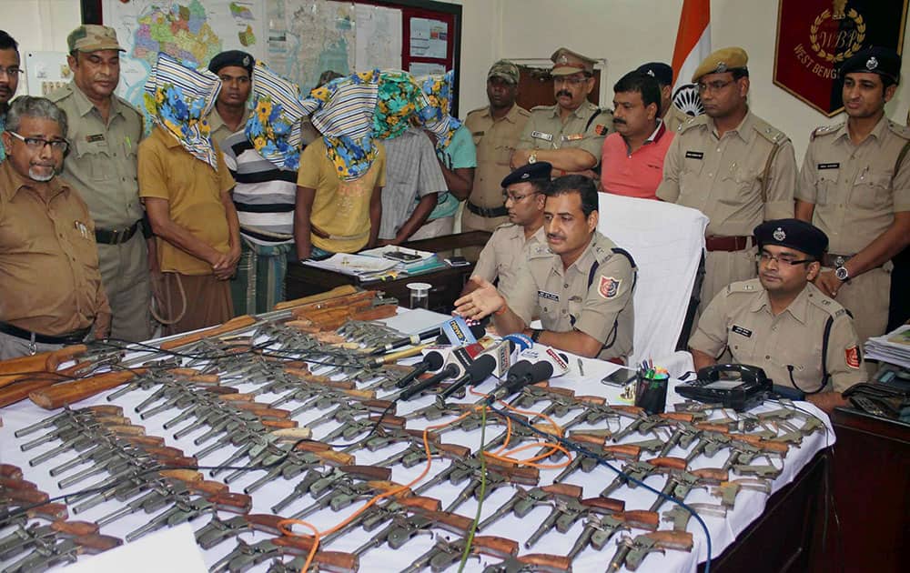 Police Superintendent Sunil Kumar Choudhary displays arms recovered from five persons (face covered), in South 24 Pargana, West Bengal