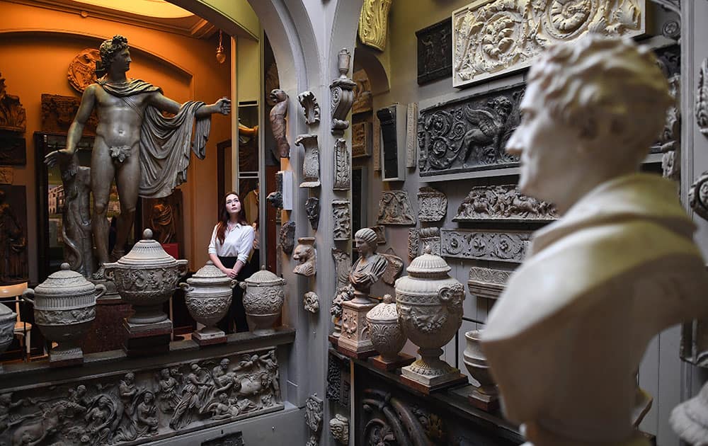 Visitor Assistant Pauline Coonan poses next to a statue of Apollo Belvedere in The Dome room of The Sir John Soanes Museum in London, England