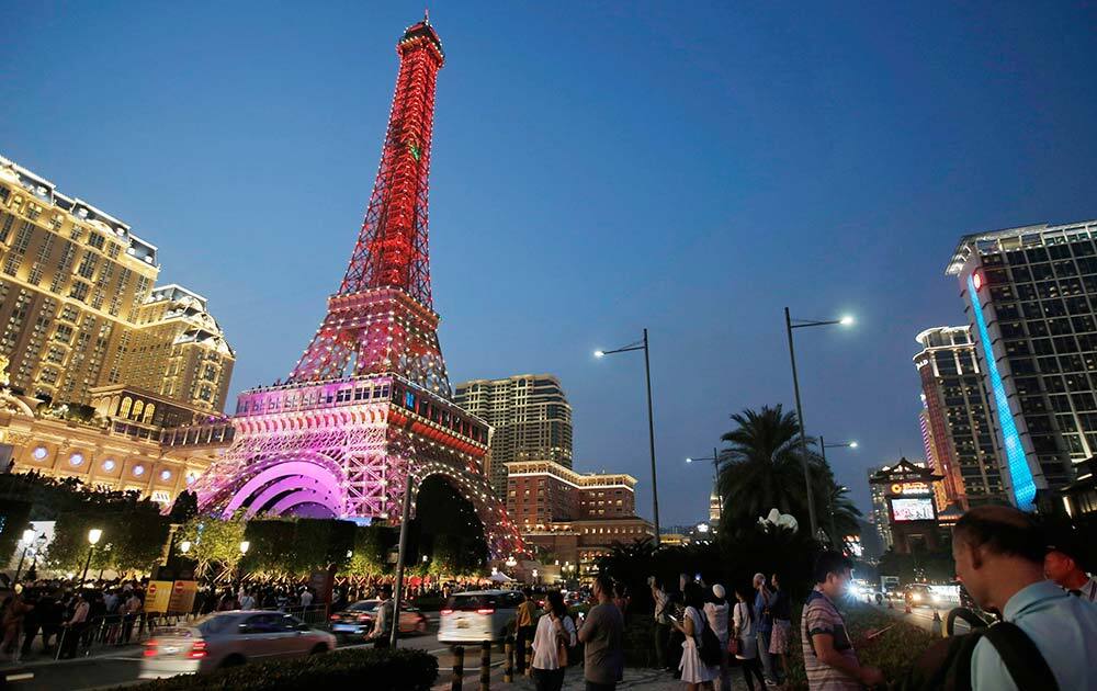 People walk in front of a replica of the Eiffel Tower