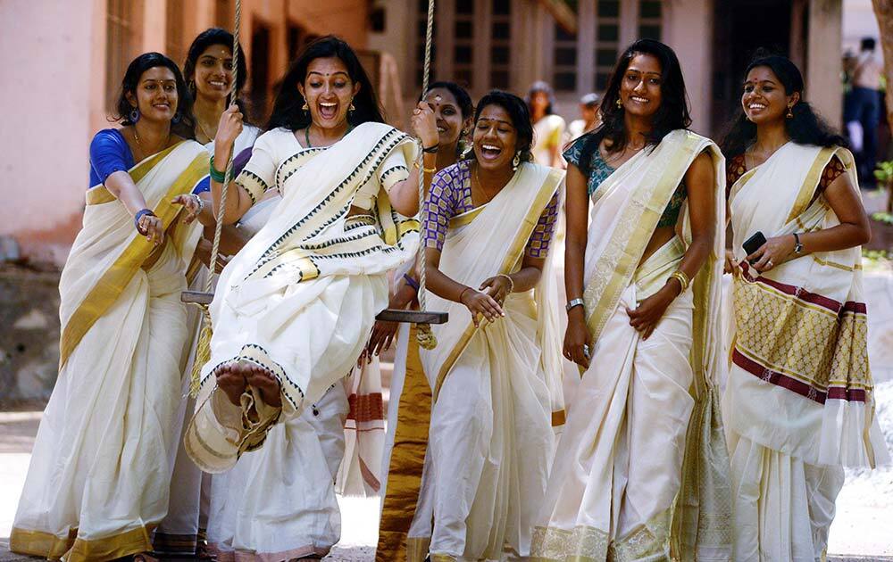 Girls enjoy on a swing during the Celebration of Onam Festival