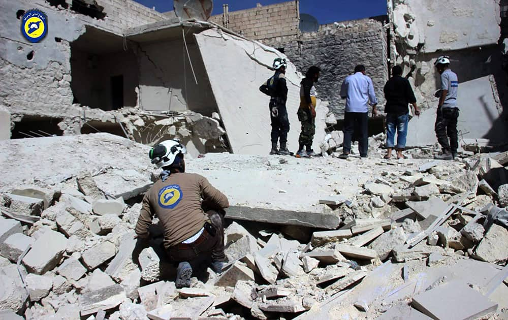 This photo provided by the Syrian Civil Defense group known as the White Helmets, shows members of Civil Defense inspecting damaged buildings after airstrikes hit the Bustan al-Qasr neighborhood of Aleppo