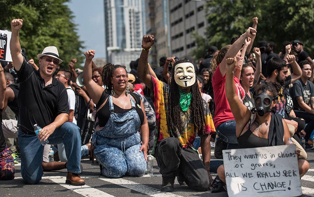 Demonstrators take a knee during the national anthem outside Bank of America Stadium