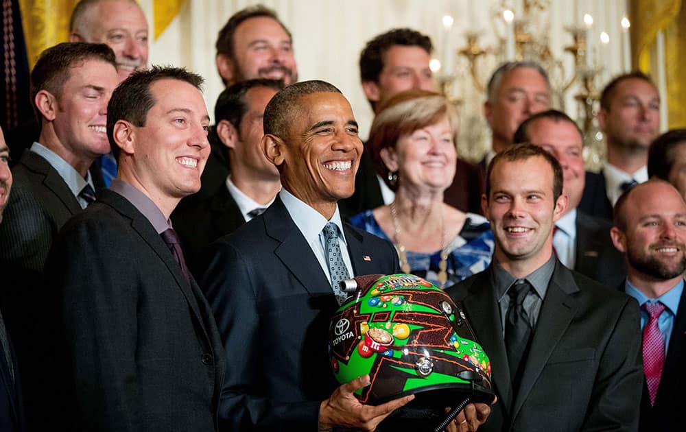 President Barack Obama holds a race car helmet and poses for a photograph with NASCAR race car driver Kyle Busch, left, and members of the Joe Gibbs Racing team