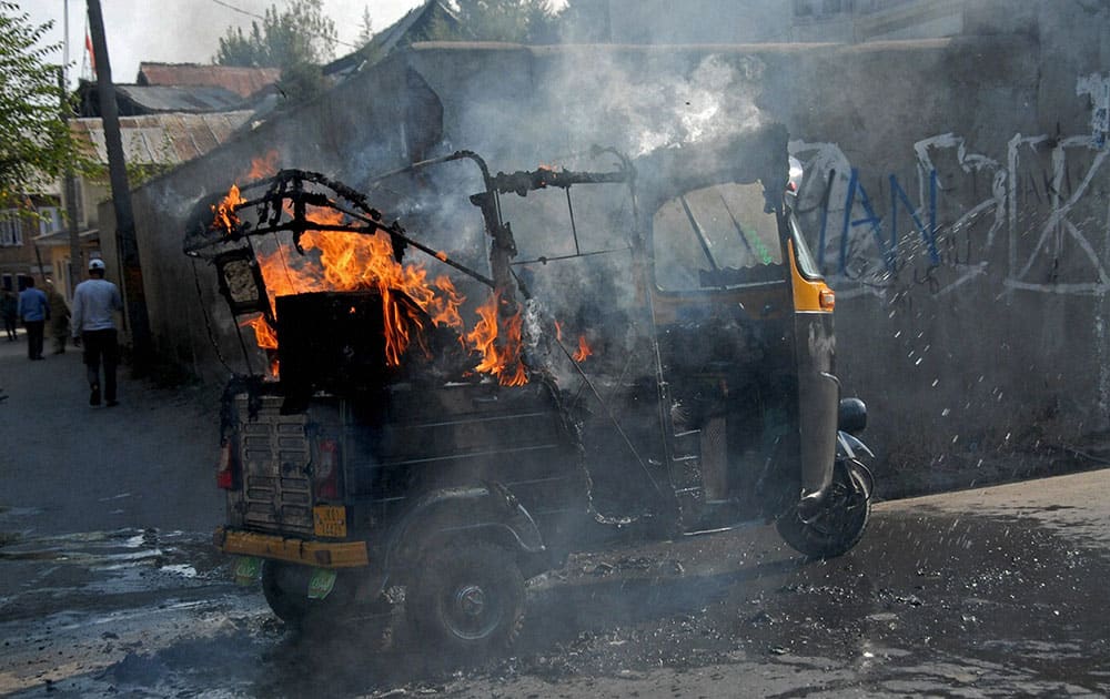 An autorickshaw in flames after it was set ablaze by a group of protesters during 88th day of strike at Saidakadal in Srinagar