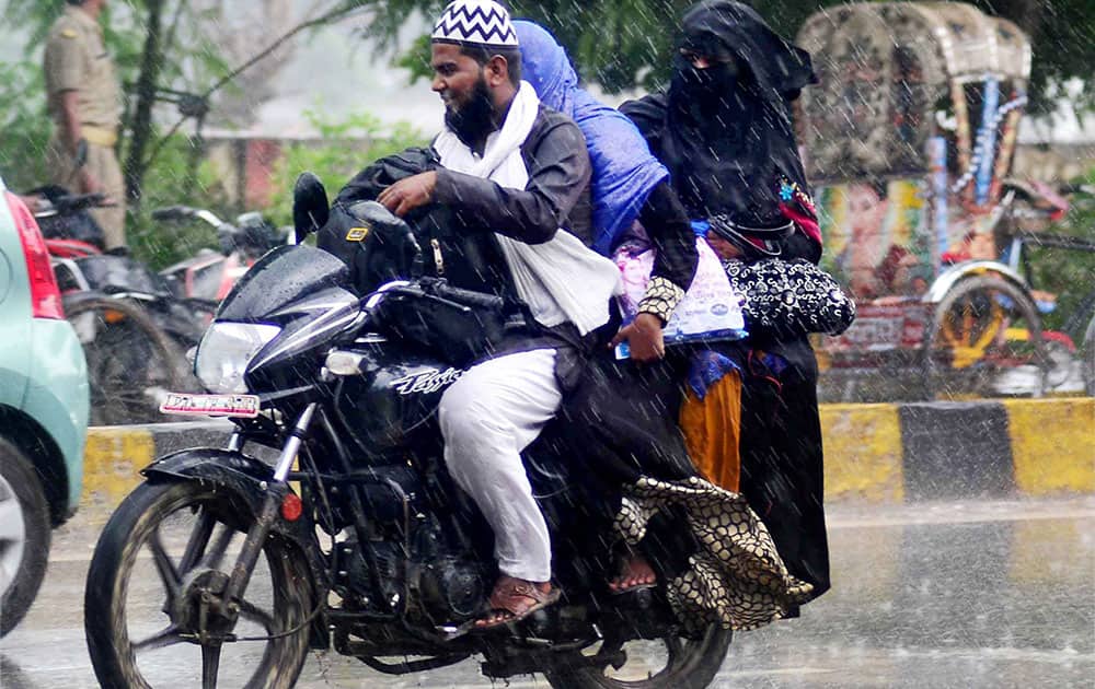 A motorcyclist drives through rainfall in Allahabad