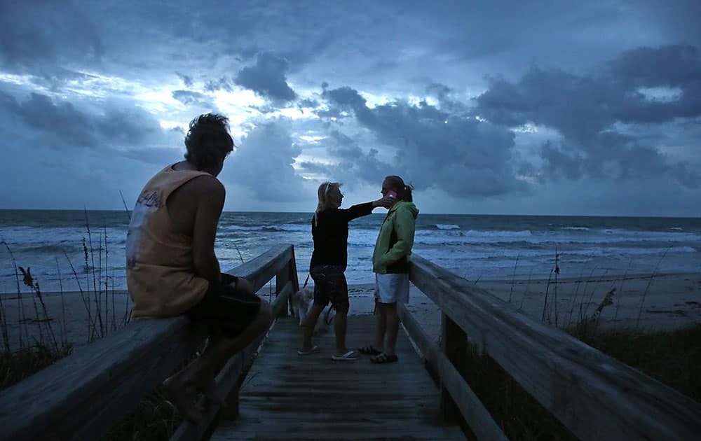 Colleen Ydo (C) reaches to hug neighbor Karen Smith (R), as her husband Rod Smith (L), sits nearby on Satellite Beach, Florida