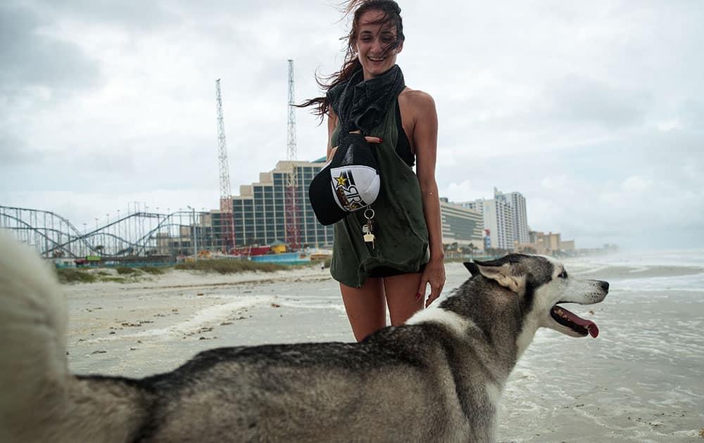 Desiree Henders and her dog Noah walk along the shoreline of Daytona Beach, in Daytona Beach, Florida