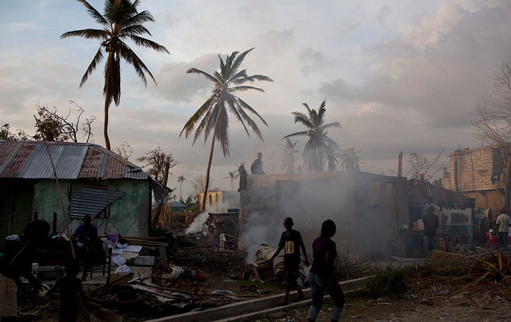 Residents burn debris and work to repair damaged homes as dusk falls in Sous-Roches, outside Les Cayes, Haiti