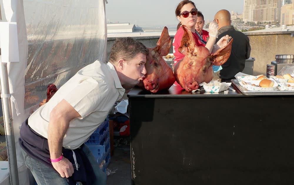 A guest kisses a pig's head at the Coca-Cola Backyard BBQ hosted by Bobby Flay and Michael Symon