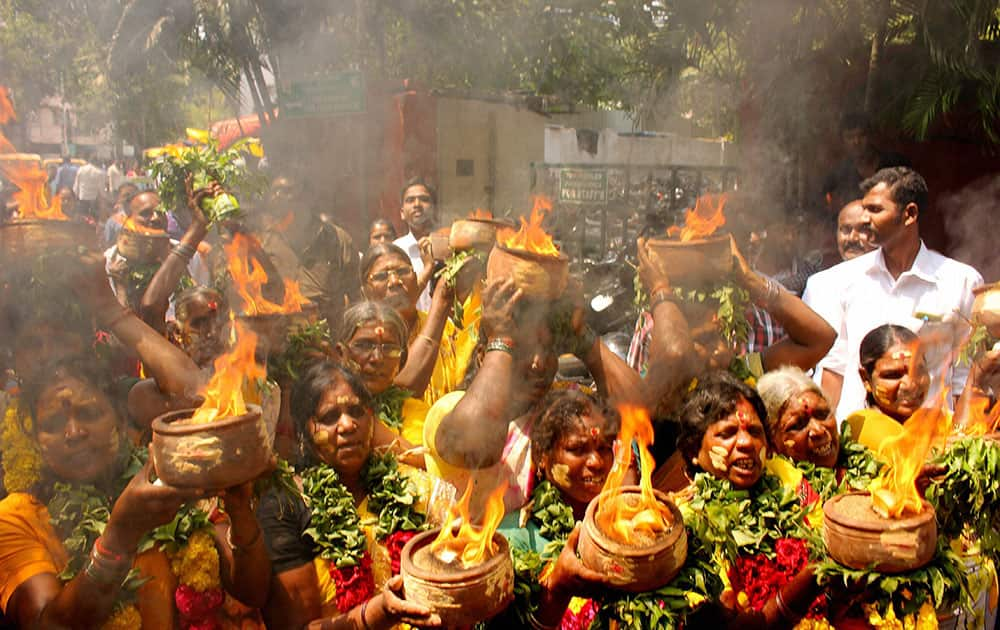 AIADMK supporters hold Fire Pots on their heads during a special prayer for speedy recovery of party supremo and Chief Minister J. Jayalalithaa