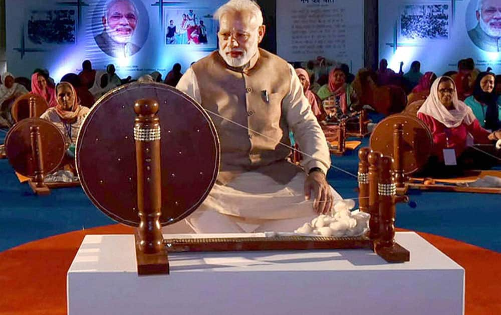 Prime Minister Narendra Modi works at a charkha