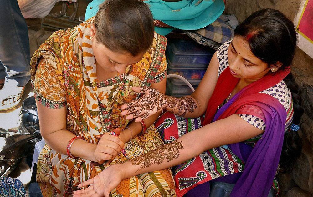 A woman gets her hand decorated with henna ahead of Karva Chauth in Ajmer