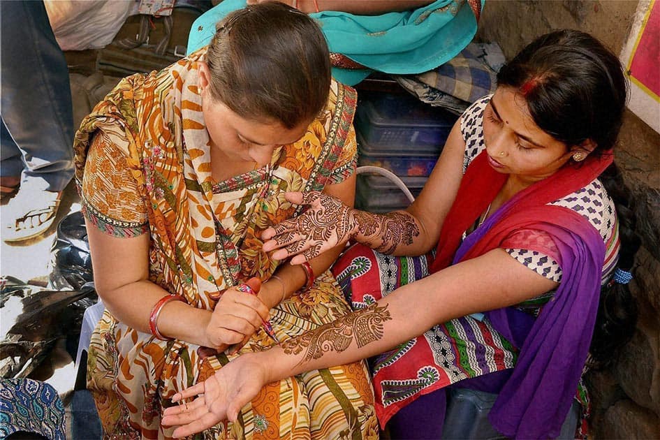 A woman gets her hand decorated with henna ahead of Karva Chauth