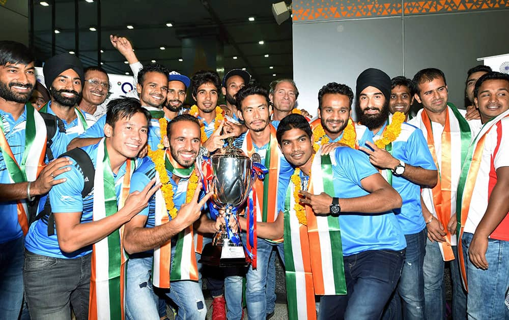 Hockey player Sardar Singh pose with the Asian Champions Trophy as they arrives at T3 terminal in New Delhi