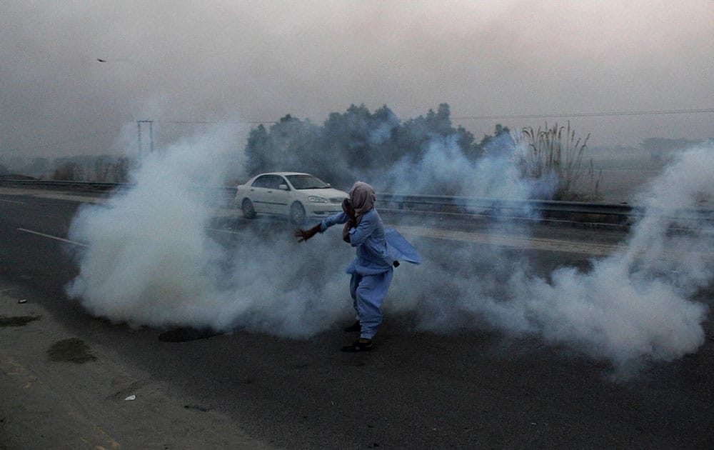 A supporter of Imran Khans Pakistan party, throws a teargas shell towards police