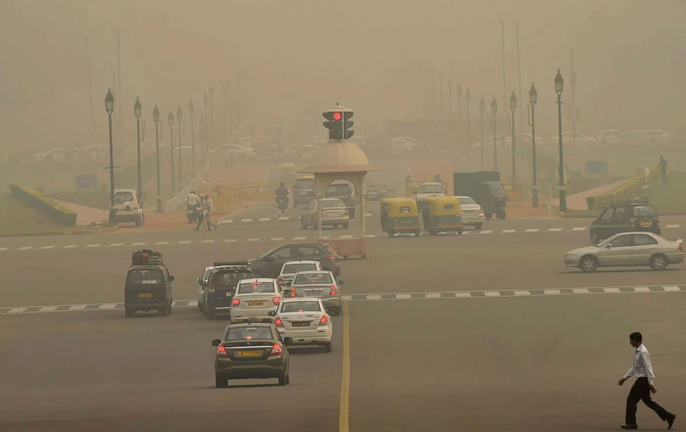 Vehicles ply at Rajpath as fog covers it in New Delhi