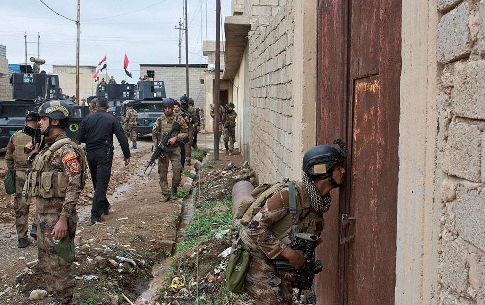 An Iraqi special forces soldier peeks through a hole in a door as his unit gets ready to search a compound