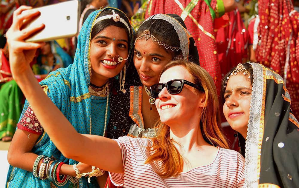 A foreign tourist takes selfies with Indian artists at Pushkar Camel Fair in Pushkar A foreign tourist takes selfies with Indian artists at Pushkar Camel Fair in Pushkar