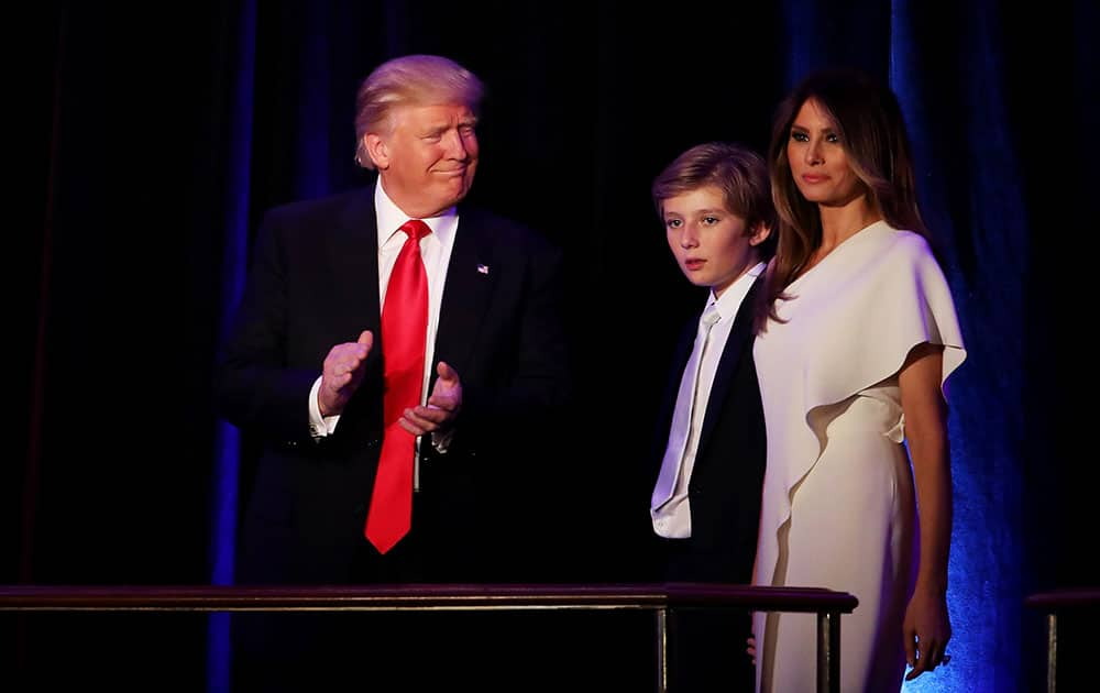 Republican president-elect Donald Trump walks on stage with his son Barron Trump and wife Melania Trump