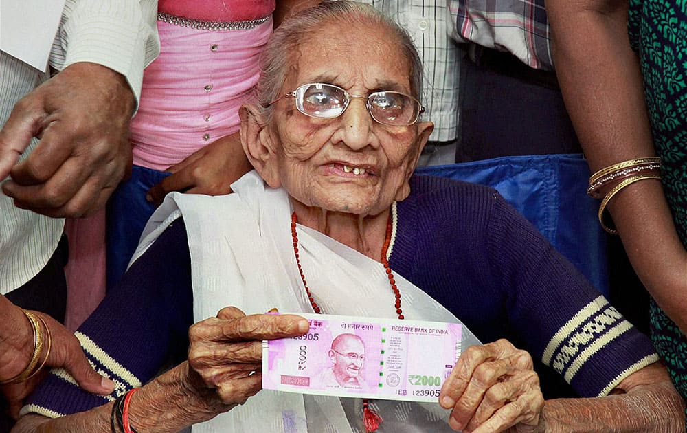 Prime Minister Narendra Modi's mother Heeraben Modi shows the 2000 rupees note after exchanging the old 500 note currency at a bank in Gandhinagar