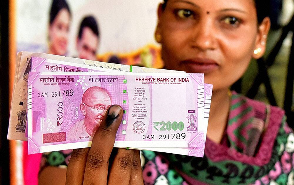 A lady display the currency notes and indelible ink after withdrawing the amount at the State Bank in Bengaluru