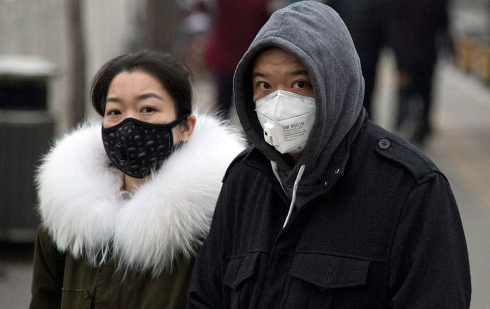 A man and woman wear masks as they walk on a street in Beijin