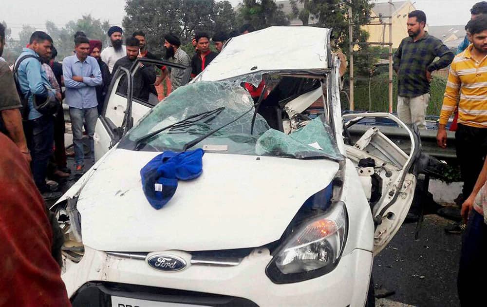 People looking at the wreackage of a car after a road accident in Jalandhar
