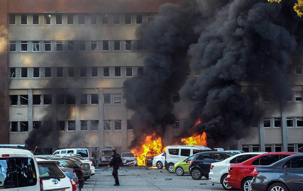 A police officer walks past by a fire after an explosion that killed people