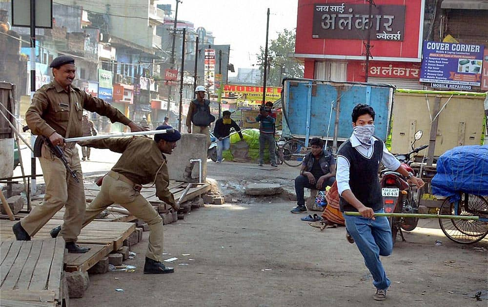 Police chase away one of the protesters who were out on a street for enforcing Jharkhand bandh