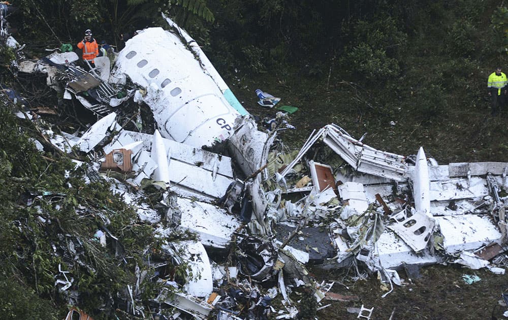 Rescue workers stand at the wreckage site of a chartered airplane that crashed outside Medellin, Colombia