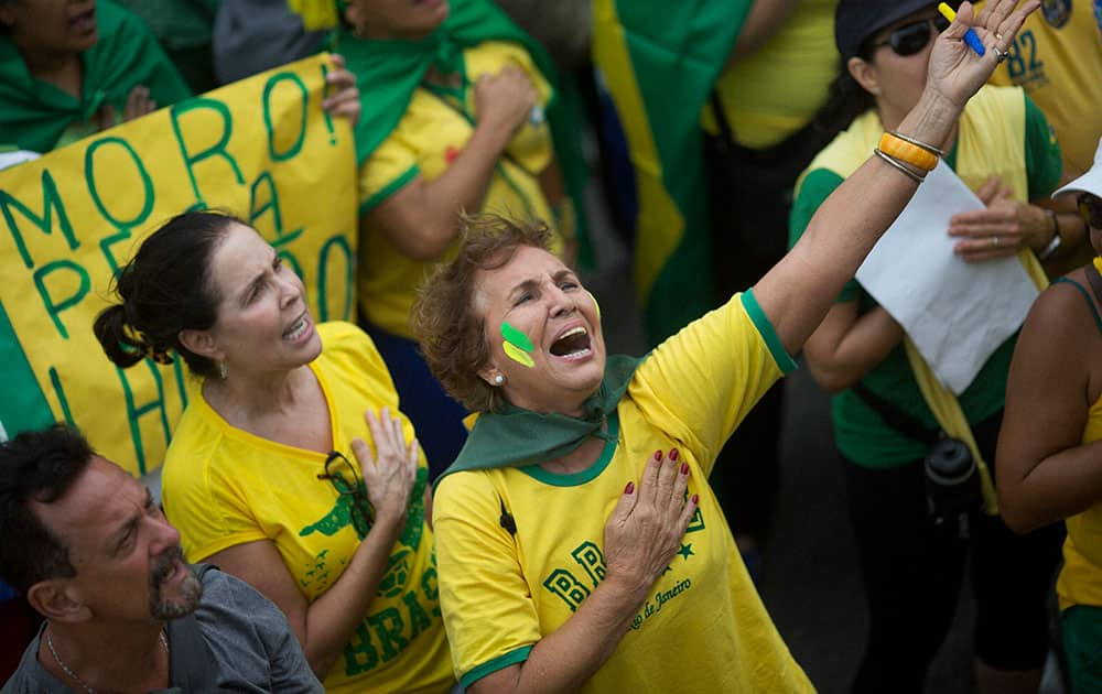 People sing the national anthem during a protest against corruption