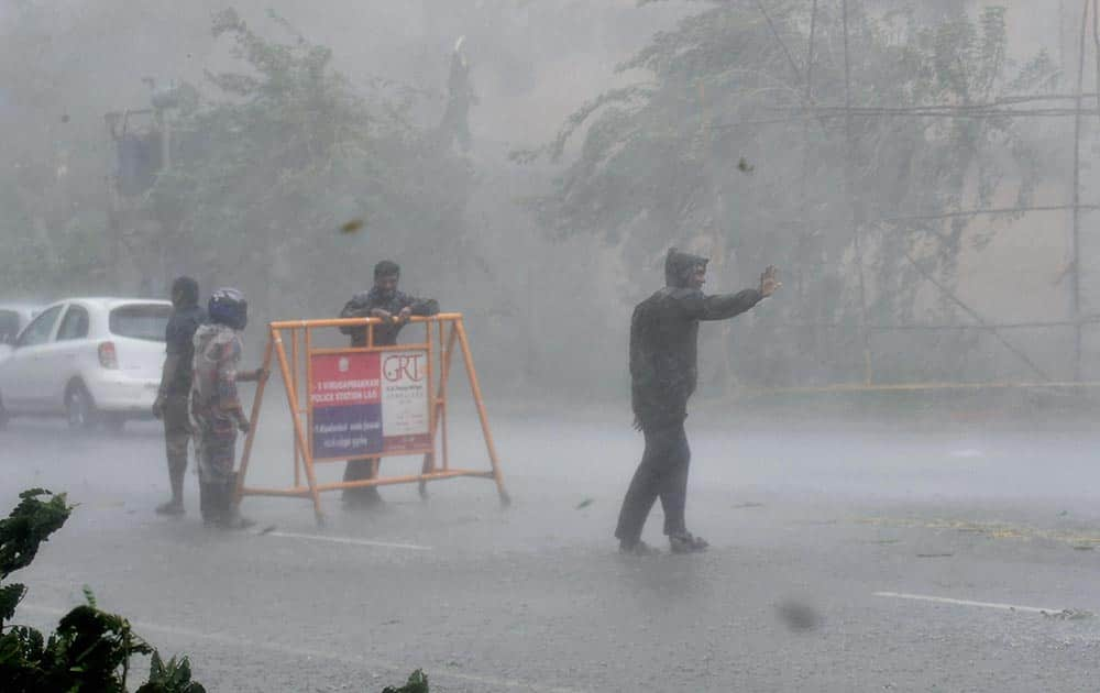 Traffic policemen guiding the traffic movement during heavy rainfall caused by Cyclone Vardah in Chennai.