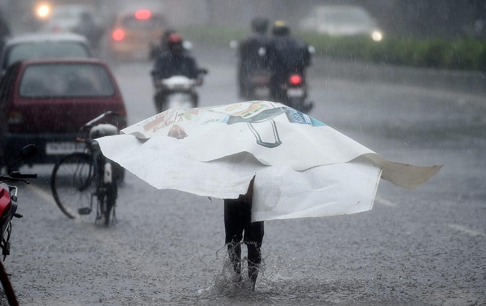 A person wades through road filled with water during heavy rainfall as cyclone Vardah made landfall near Chennai coast.