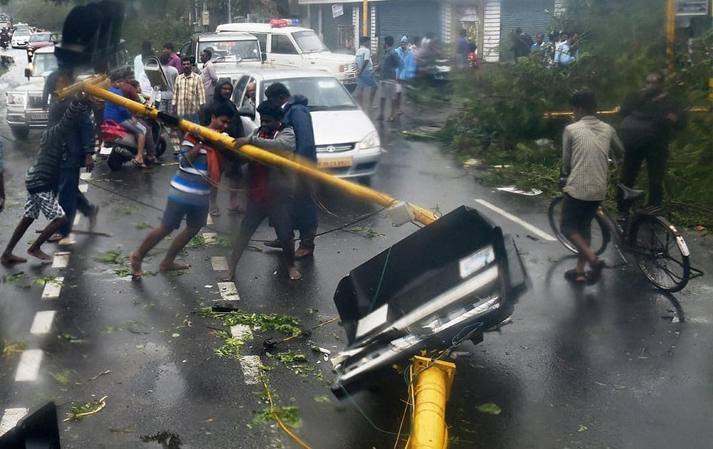 People lifting uprooted poles following a storm in Chennai 