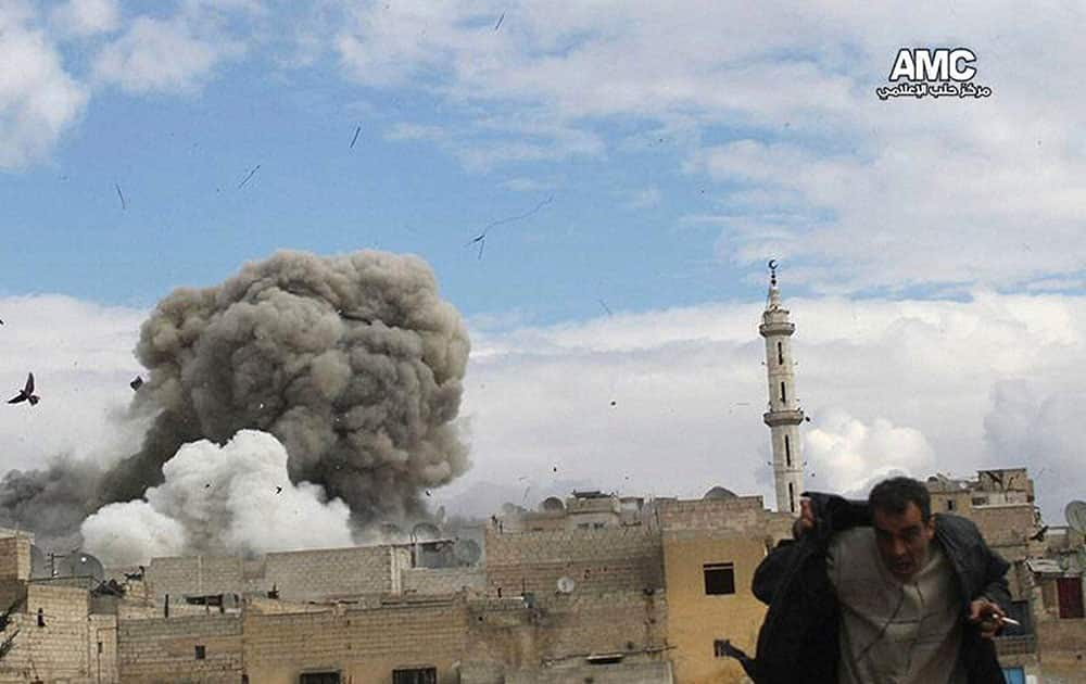 A Syrian man runs for cover from a Syrian government forces airstrike attack