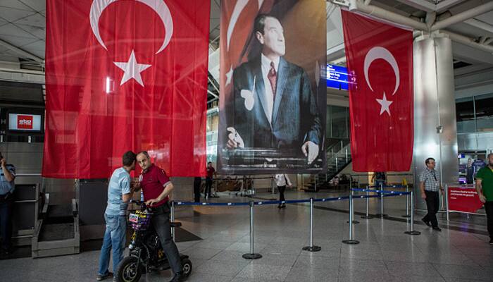 Men greet each other in front of Turkish flag and picture of modern Turkey's founder Mustafa Kemal Ataturk at Istanbul Ataturk airport on June 29, 2016 in Istanbul, Turkey. 