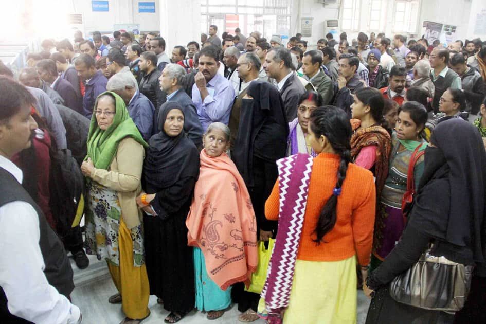 People stand in long queues to withdraw cash