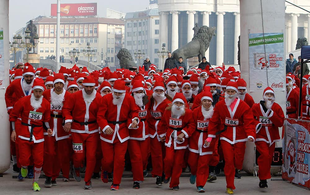 People dressed in Santa Claus costumes run at the start of a Santa Claus Race